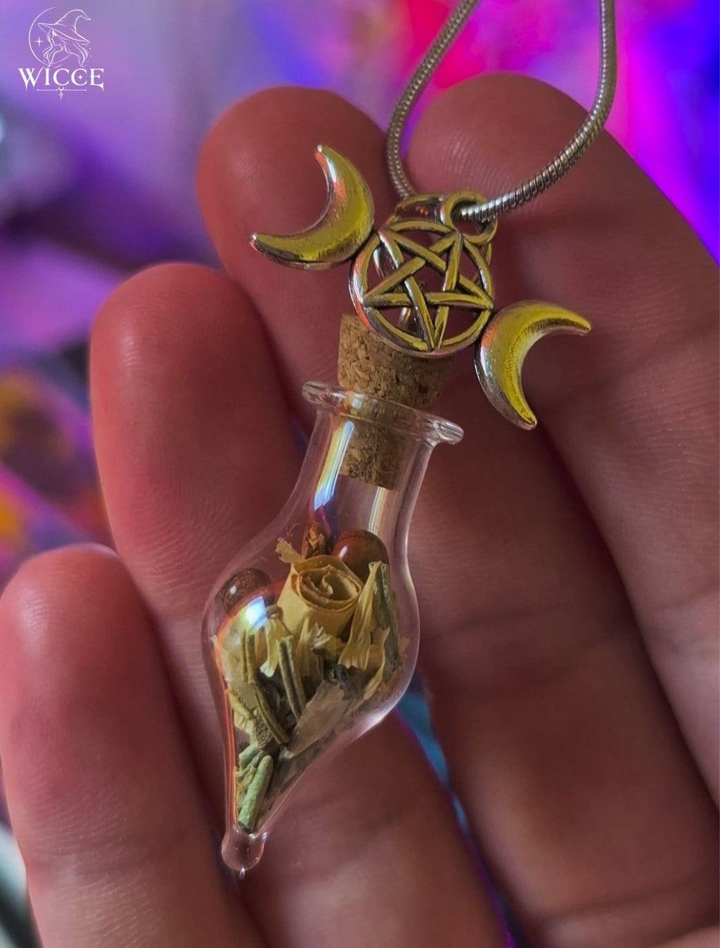 Business success talisman necklace with a triple moon - pentagram charm, glass vial filled with herbs and jasper held by hand.