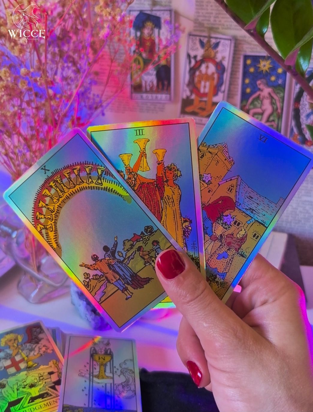 Friendship Check-Up Tarot Reading with three holographic tarot cards held by a hand with red nail polish.