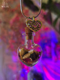 Love talisman necklace with a heart charm, glass vial filled with rose petals, jasmine and herbs.