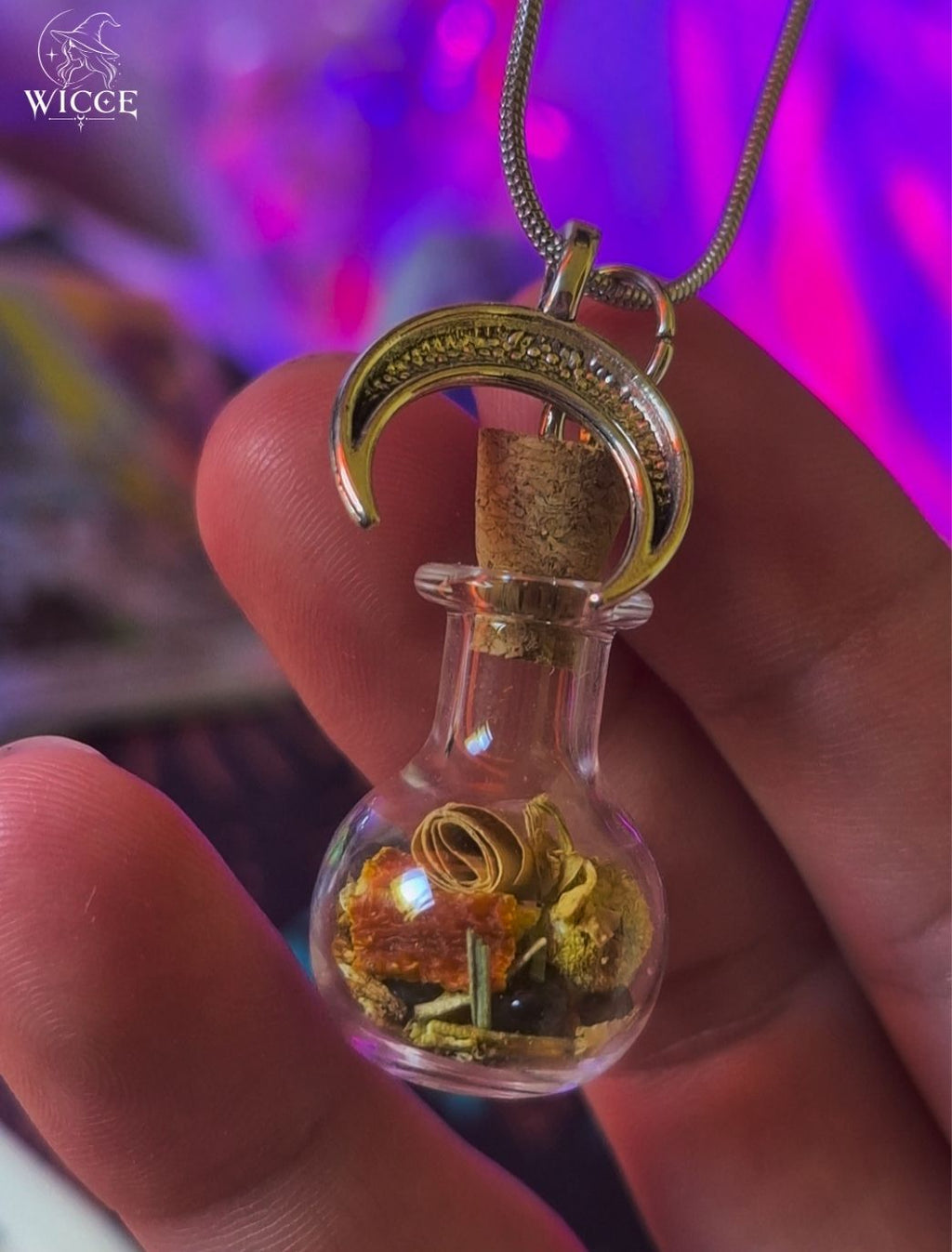 New Beginnings talisman necklace with a crescent moon charm, glass vial filled with herbs and amethyst held by hand.